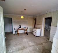 An abandoned room with an old stove and a table in a family house.