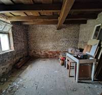 A storage space with old brick walls and a wooden ceiling in a family house.