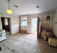 An abandoned kitchen in a family house with damaged walls and neglected furniture.