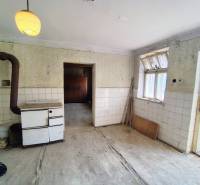 An older kitchen in a family house with a tiled stove and a glazed window.