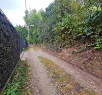 A narrow path with a gravel surface in Bratislava - Dúbravka, Tavarikova osada, lined with fencing and greenery.
