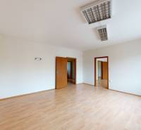 A spacious room of a family house with laminate flooring and a large window.
