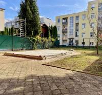 The courtyard of a family house on Hurbanova Street in Trenčín with paving and trees in the garden.