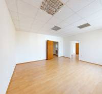 A room in a family house with white walls, laminate flooring, and wooden doors.