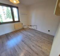 A room with a light floor in a 4-room apartment, large window, radiator, empty walls.