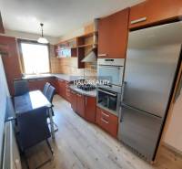 A kitchen in a 4-room apartment with built-in appliances and a dining table.