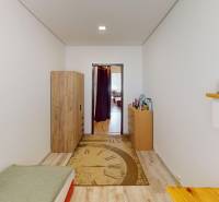 A narrow room in a 3-room apartment with a bed, wardrobe, and a shelf on the wall.