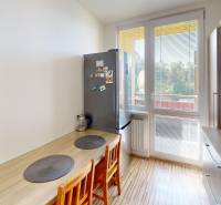 A kitchen in a 3-room apartment with a table, chairs, a refrigerator, and a view of the balcony.