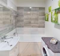 A bathroom in a 3-room apartment with a bathtub, sink, and washing machine, decorated with floral motifs.