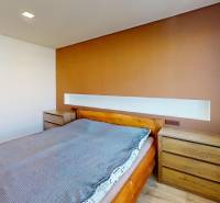 A bedroom in a 3-room apartment with a wooden bed and two dressers by the window.
