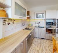 A kitchen in a 3-room apartment with light furniture and wall decorations.