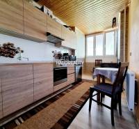 A kitchen in a 2-room apartment with wooden cabinets and a table.