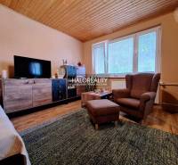 Living room in a two-room apartment with a sofa, an armchair, and a TV wall.