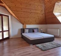 Attic bedroom in a family house with wooden paneling, skylights, and a bed.
