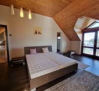 Attic bedroom in a family house with wooden paneling and a double bed.