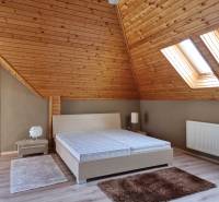 Attic bedroom with a wooden ceiling and skylights in a family house.
