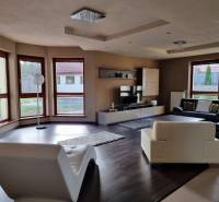 Living room in a family house with comfortable seating and large windows.