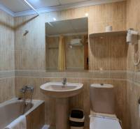Bathroom in a Holiday Apartment with a bathtub, sink, and mirror.