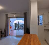 Kitchenette in a holiday apartment with a dining table and a view of the terrace.