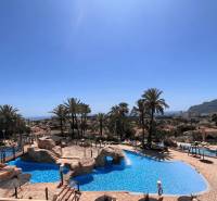 A pool with palm trees and a sea view in a holiday apartment in Calp.