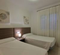 Two single beds, a nightstand with a lamp, and curtains in the vacation apartment.