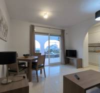Living room of a holiday apartment with a view of the balcony and an attached kitchen.