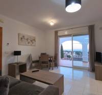 Living room in a holiday apartment with a sofa, table, and view of the terrace.