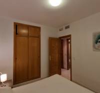 A bedroom in a holiday apartment with a bed, wardrobe, and decorative paintings on the walls.