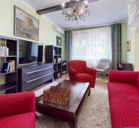Living room in a 3-room apartment with red sofas, a shelving cabinet, and a chandelier.