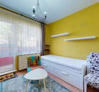 A room in a 3-room apartment with a sofa, an armchair, and a table, yellow walls, wooden floor.