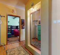 A hallway with a mirror, a green wardrobe, and a view into a cozy living room in a 3-room apartment.