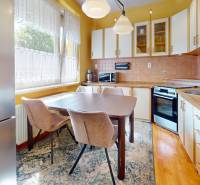 The kitchen of a three-room apartment with a dining table, refrigerator, and built-in appliances.