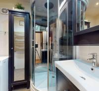 A bathroom in a 3-room apartment with a washing machine, shower corner, and mirrored cabinet.