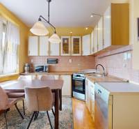 A kitchen in a 3-room apartment with a wooden table and pastel chairs.