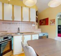 A kitchen with wooden doors and appliances in a 3-room apartment with a dining table.