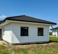 A family house in Mostová with a dark roof on a grassy plot on a sunny day.