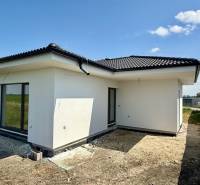 A family house in Mostová with a white facade and a sloped roof on an open plot.