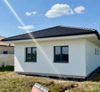 A family house in Mostová with a white facade and a black roof on a spacious plot.