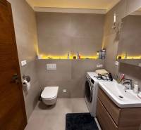 Bathroom with a bathtub and a washing machine in a 2-room apartment, storage space with a sink.