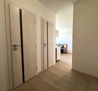 A bright hallway in a 3-room apartment with light-colored doors and entrance to the kitchen.
