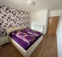 A bedroom in a 3-room apartment with white furniture and purple decorations on the wall.