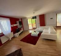 A spacious living room in a 3-room apartment with white furniture and red walls.