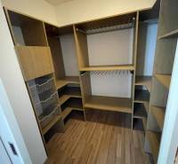 A wardrobe with wooden shelves and storage baskets in a 3-room apartment.