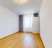 An empty room with wooden flooring and curtains in a 2-room apartment.