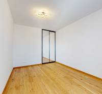 A room in a 2-room apartment with a wooden floor and a built-in wardrobe.