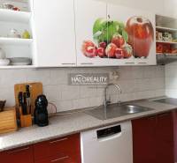 A kitchen in a 3-room apartment with white cabinets and a fruit motif on the doors.