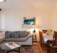 Living room in a three-room apartment with a large sofa and a wooden dining table.