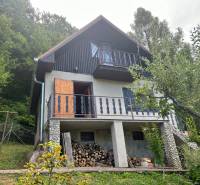 A cabin in the woods with a wooden balcony, wood storage, nature, greenery, relaxation in a natural environment.