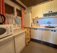 A kitchen in a cabin with a microwave, kettle, shelves, cabinets, and a rustic interior for pleasant stays.