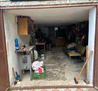 A garage with open doors, various tools, a loosely placed axe, in a country cottage.